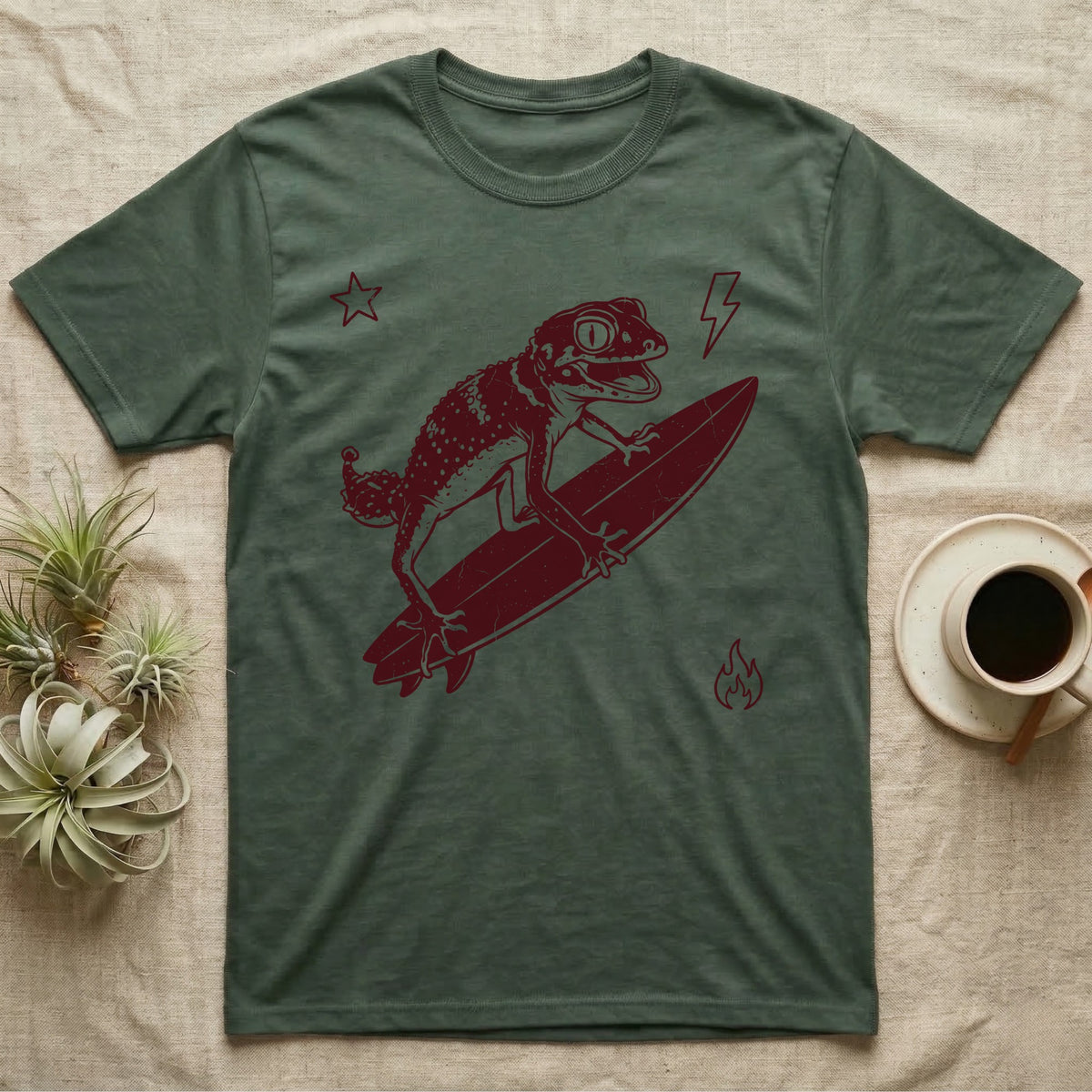 Knob-Tailed Gecko Surfing T-Shirt in Military Green — Distressed one-ink illustration of a knob-tailed gecko riding a surfboard, airborne at the peak of an aerial.