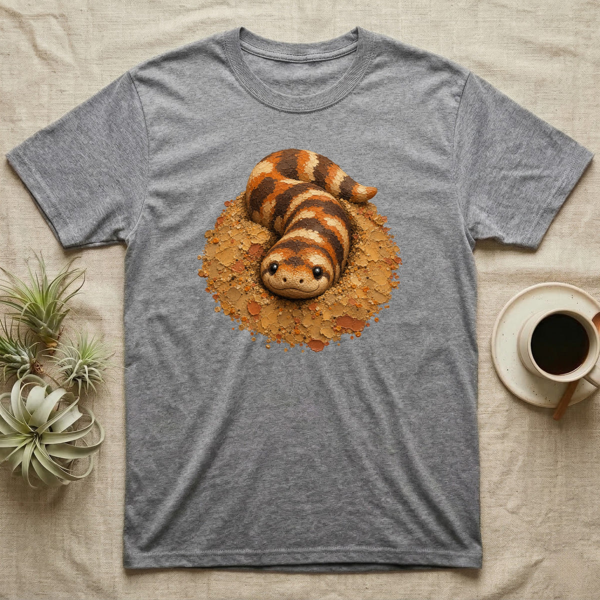 Grey t-shirt with a cartoon desert sand boa illustration on a neutral background.