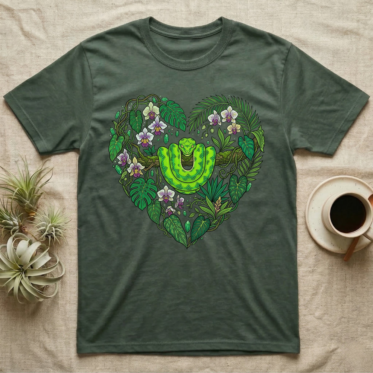 Green snake and tropical plants forming a heart shape on a dark green t-shirt.