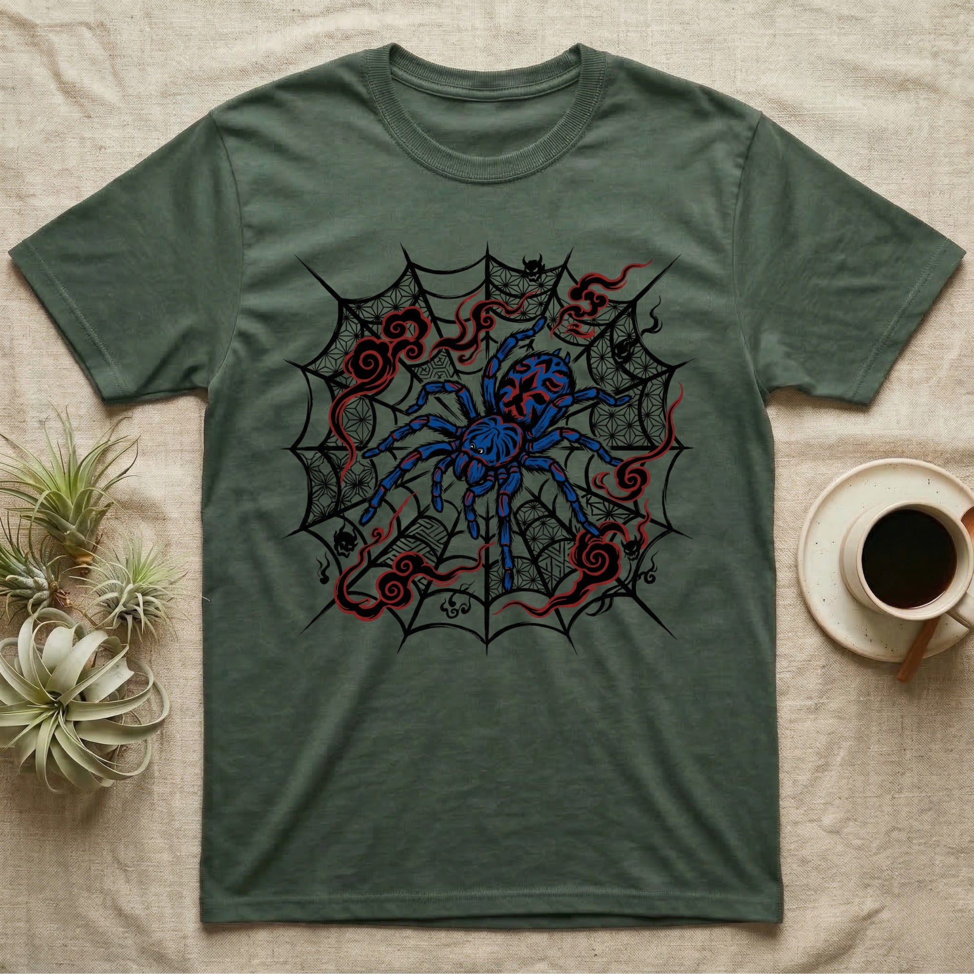 Green t-shirt with a blue and red spider design on a web.