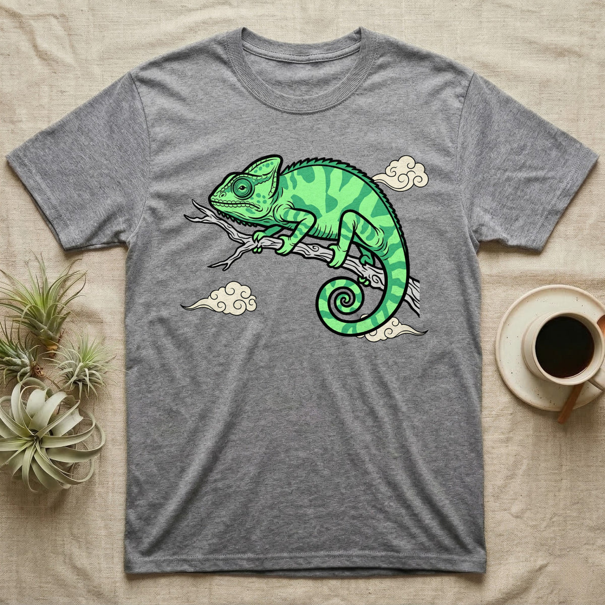 Gray t-shirt with a green chameleon on a branch with clouds.