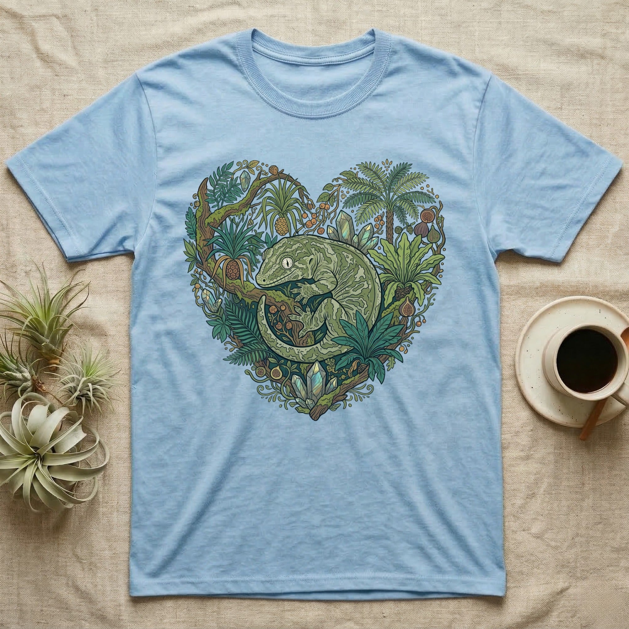 Light blue t-shirt with a heart-shaped design of a gecko amidst lush tropical foliage.