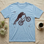 Tree Frog BMX T-Shirt in Light Blue — One-ink worn screen print of a White's tree frog riding a BMX bike mid-air, body stretched straight out behind the handlebars.