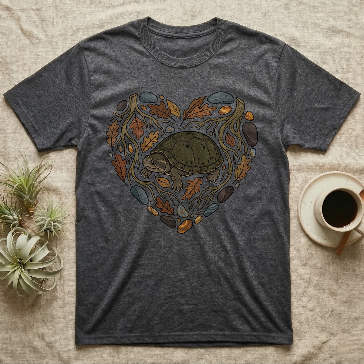 Grey t-shirt with a heart-shaped design of a turtle, leaves, and stones.