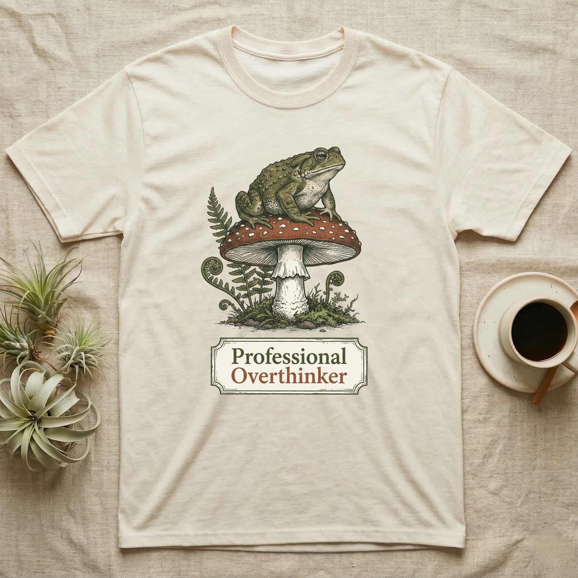 Cream t-shirt with frog on mushroom design, text "Professional Overthinker".