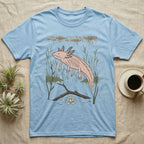 Axolotl Home Range T-Shirt in Light Blue — Woodcut-style illustration of an axolotl drifting among reeds and lily pads in a Xochimilco canal, no on-shirt text.