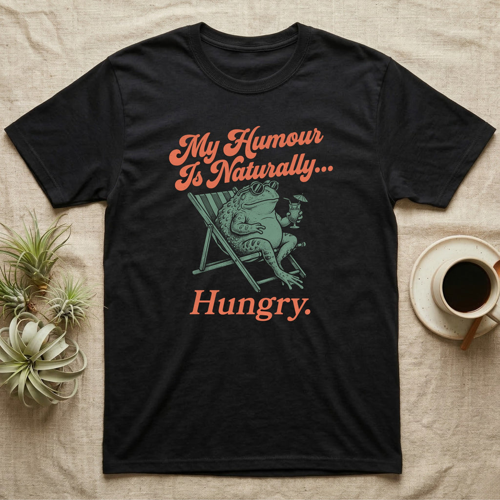African Bullfrog Sun Lounger T-Shirt in Black — Illustrated African bullfrog reclining in a beach chair with sunglasses and a cocktail, retro coral script reading My Humour Is Naturally Hungry.