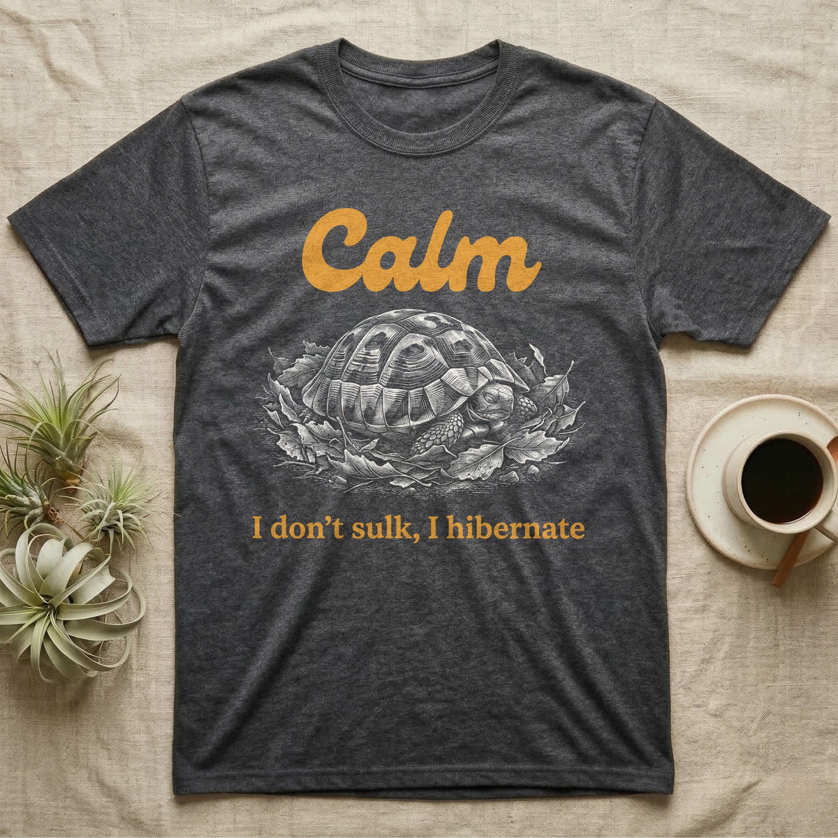 Hermann's Tortoise Calm T-Shirt in Dark Heather — White-line engraving of a Hermann's tortoise tucked into its shell in dry leaves under the word Calm