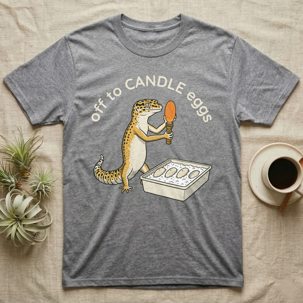 Leopard Gecko Candling T-Shirt in Sport Grey — Leopard gecko holding a torch under a glowing orange egg beside a tub of eggs, under the words off to CANDLE eggs