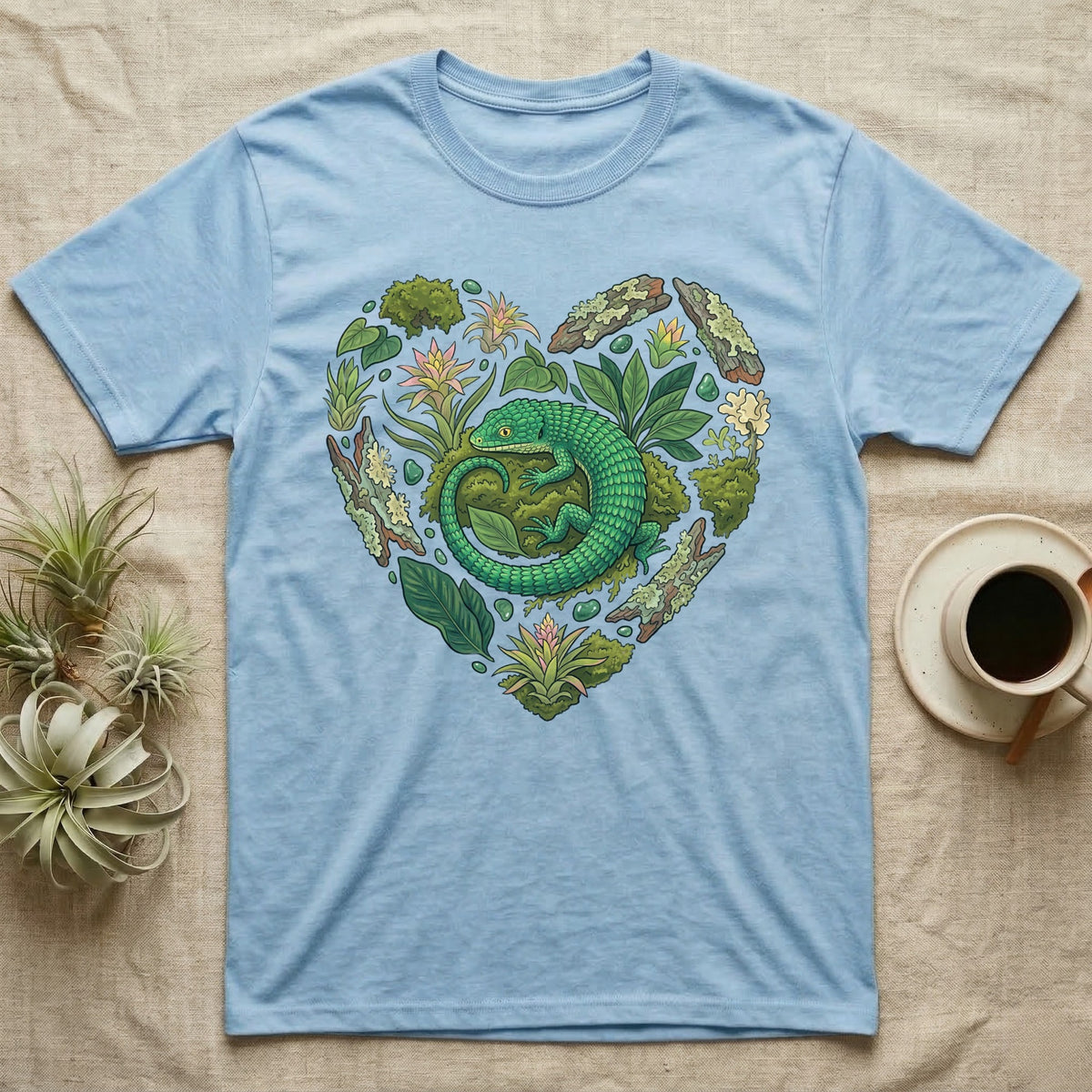 Blue t-shirt with a green lizard and plants forming a heart shape.