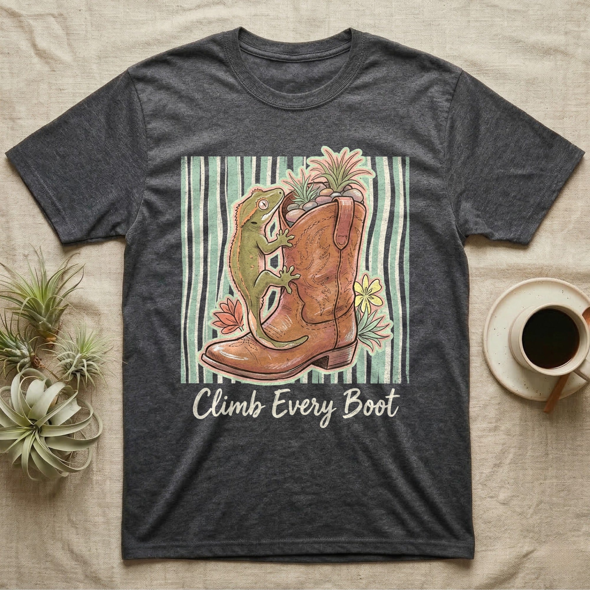 Dark grey t-shirt with green gecko climbing a cowboy boot with flowers.