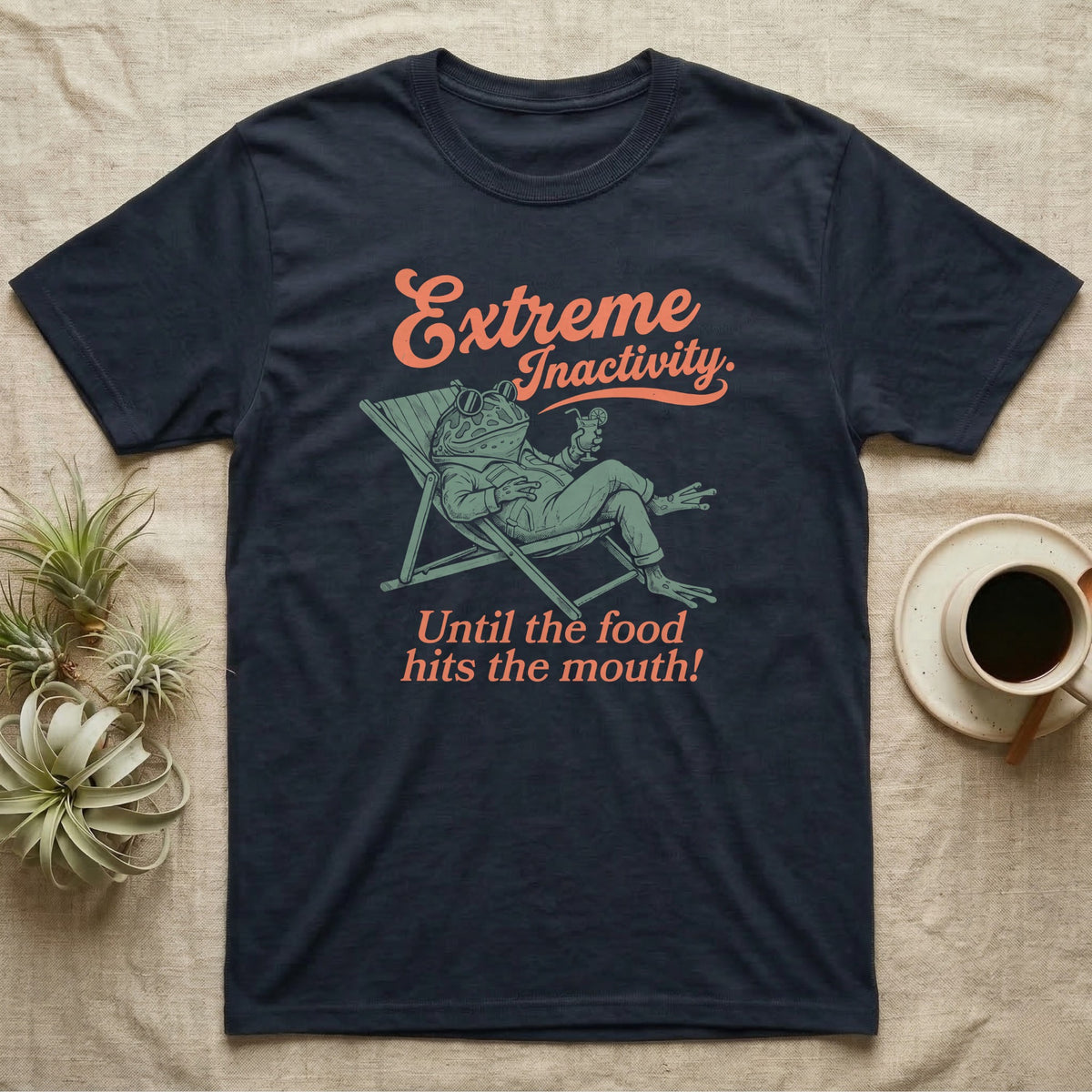 Pacman Frog Lazy Day T-Shirt in Navy — Illustrated pacman frog reclining in a beach chair in a jacket with sunglasses and a cocktail, coral script reading Extreme Inactivity Until The Food Hits The Mouth.