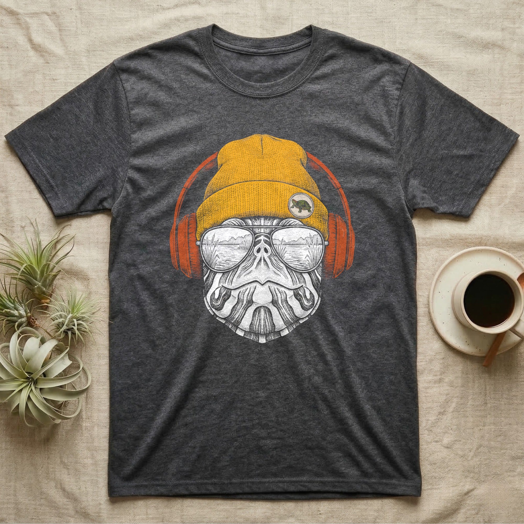 Red-Eared Slider Headphones T-Shirt in Dark Heather — Engraved red-eared slider turtle in a beanie and headphones, aviators reflecting a calm reed-lined lake.