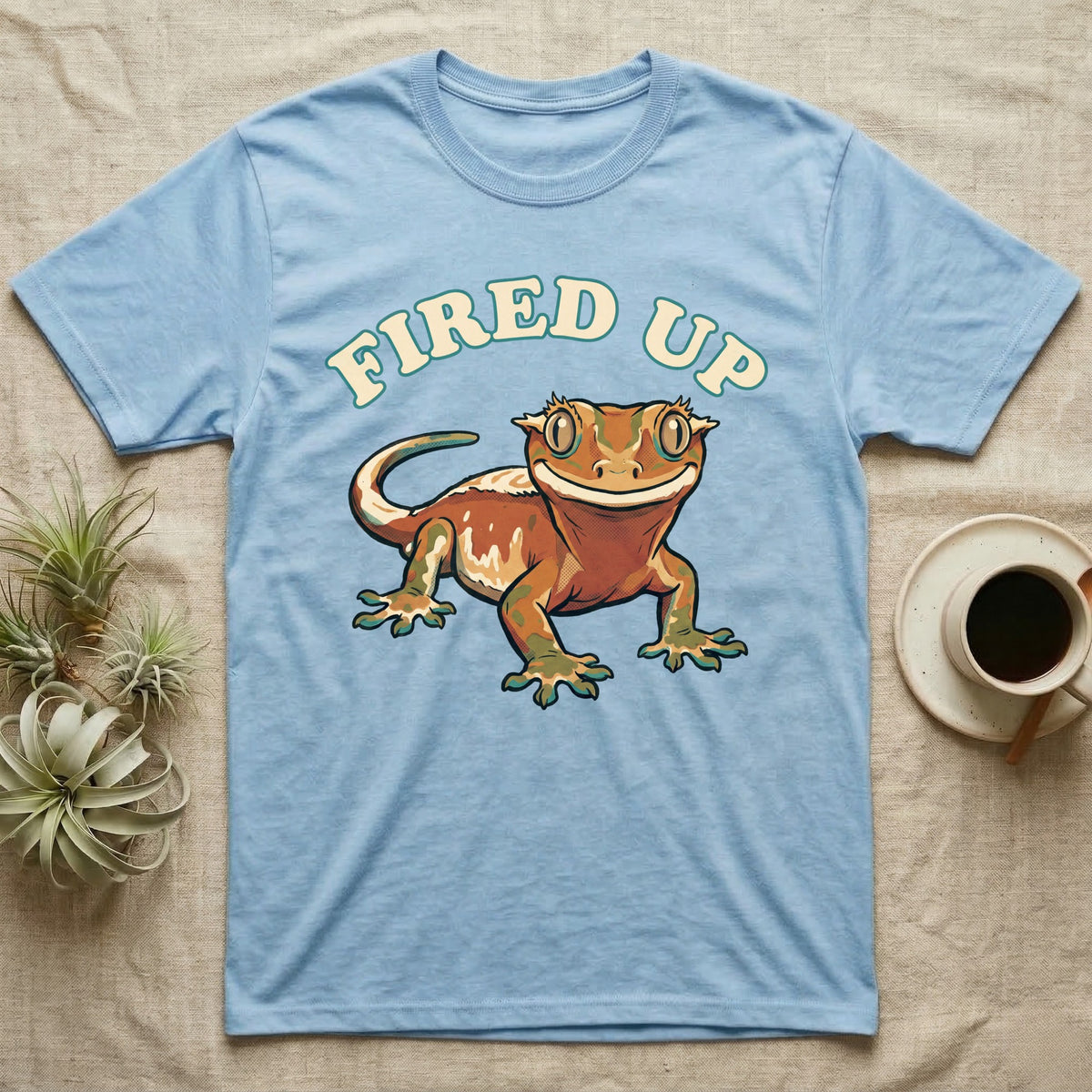 Fired Up Crested Gecko T-Shirt in Light Blue — Retro 90s-style illustration of a fired-up crested gecko under a bold arc headline reading Fired Up.