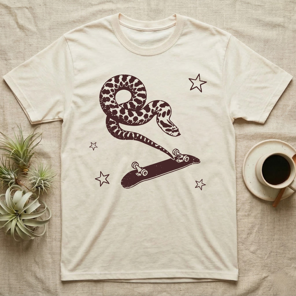 Western Hognose Kickflip T-Shirt in Natural — Distressed one-ink oxblood screenprint of a western hognose snake airborne, tail snapped straight into a skateboard caught upside down mid-kickflip.