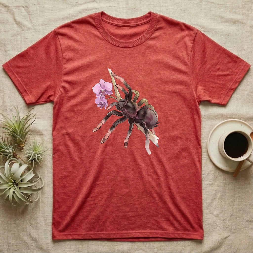 Pink-Toe Tarantula Blossom T-Shirt in Heather Red — Watercolor illustration of a charcoal pink-toe tarantula with salmon toe tips holding an orchid blossom sprig, on a dark grey t-shirt.
