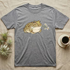 Pacman Frog Blossom T-Shirt in Sport Grey — Watercolor illustration of an olive-tan Pacman frog holding a water-lily blossom sprig, on a dark grey t-shirt.