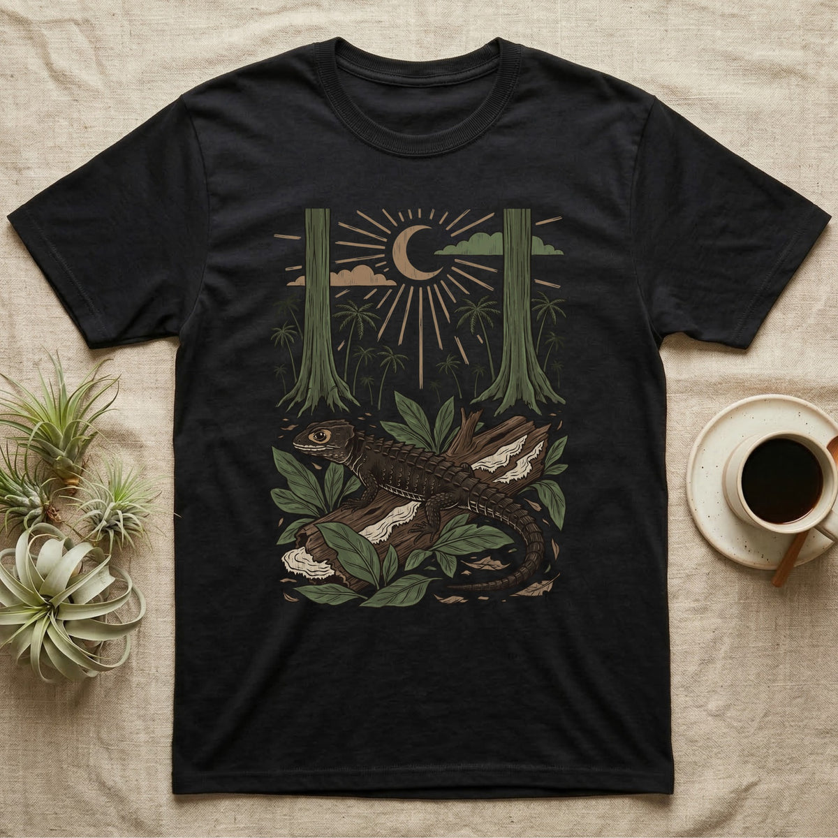 Crocodile Skink Home Range T-Shirt in Black — Woodcut-style illustration of a red-eyed crocodile skink crouched on a rainforest log among broad leaves and palms, no on-shirt text.