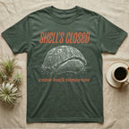 Box Turtle Shell's Closed T-Shirt in Military Green — Engraved white-line eastern box turtle shut tight under retro orange script reading SHELL'S CLOSED, come back tomorrow.