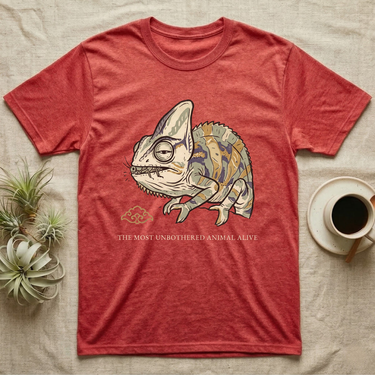 Unbothered Chameleon T-Shirt in Heather Red — Ukiyo-e woodblock illustration of a veiled chameleon mid-chew with a deadpan serif caption beneath the subject.