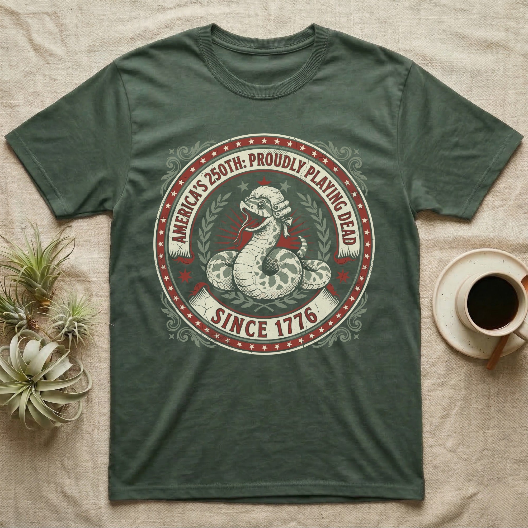 Hognose Snake 1776 Tee in Military Green — Vintage circular seal of a hognose snake playing dead belly-up in a colonial wig, brick-red and cream emblem reading Proudly Playing Dead Since 1776.