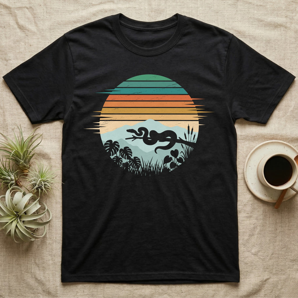 Ball Python Retro Sunset T-Shirt in Black — Ball python silhouette draped over a branch inside a retro striped sunset disc with monstera leaves on a tee