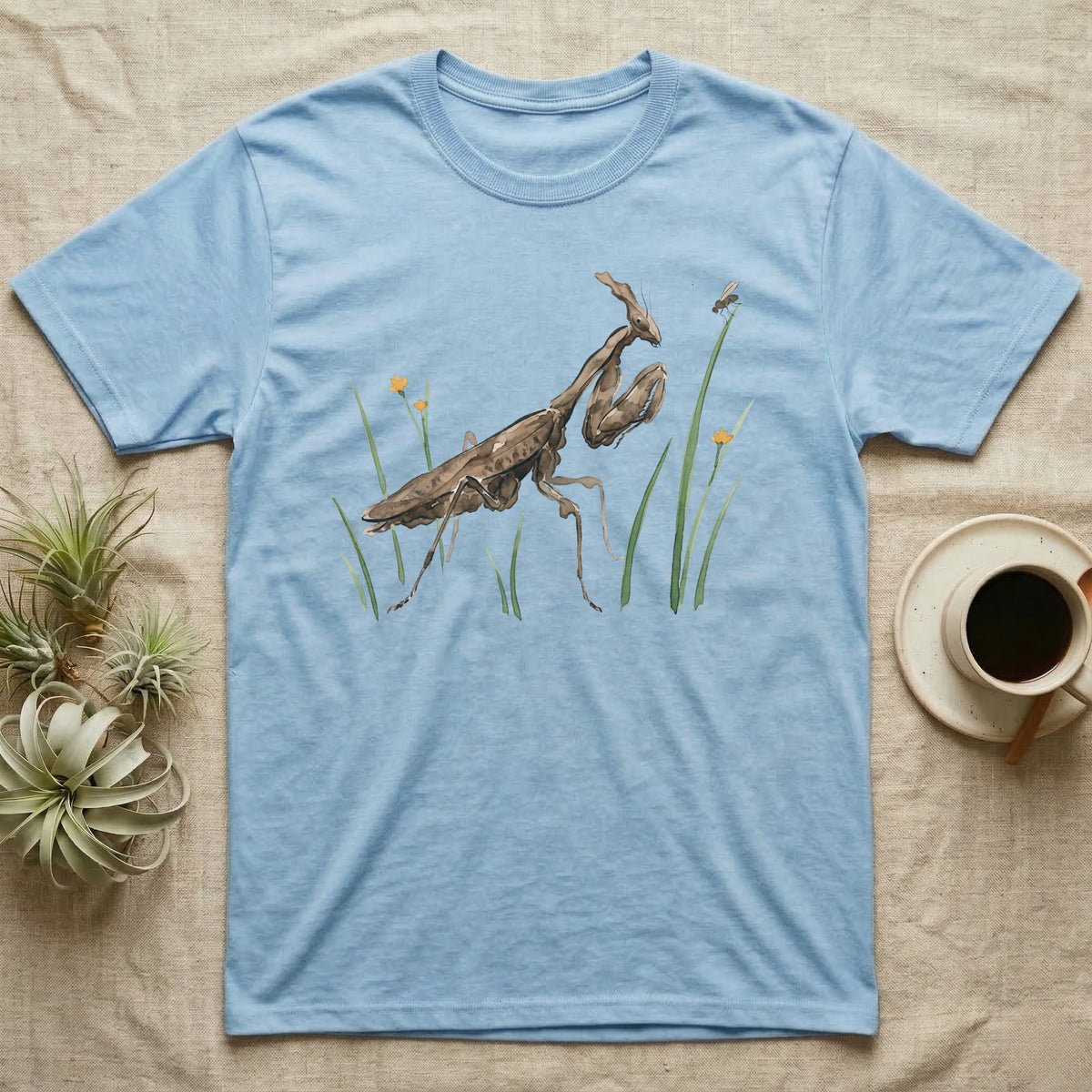 Ghost Mantis Watercolour T-Shirt in Light Blue — Watercolour ghost mantis standing still in profile with forelegs folded, watching a single fruit fly perched on a grass tip.