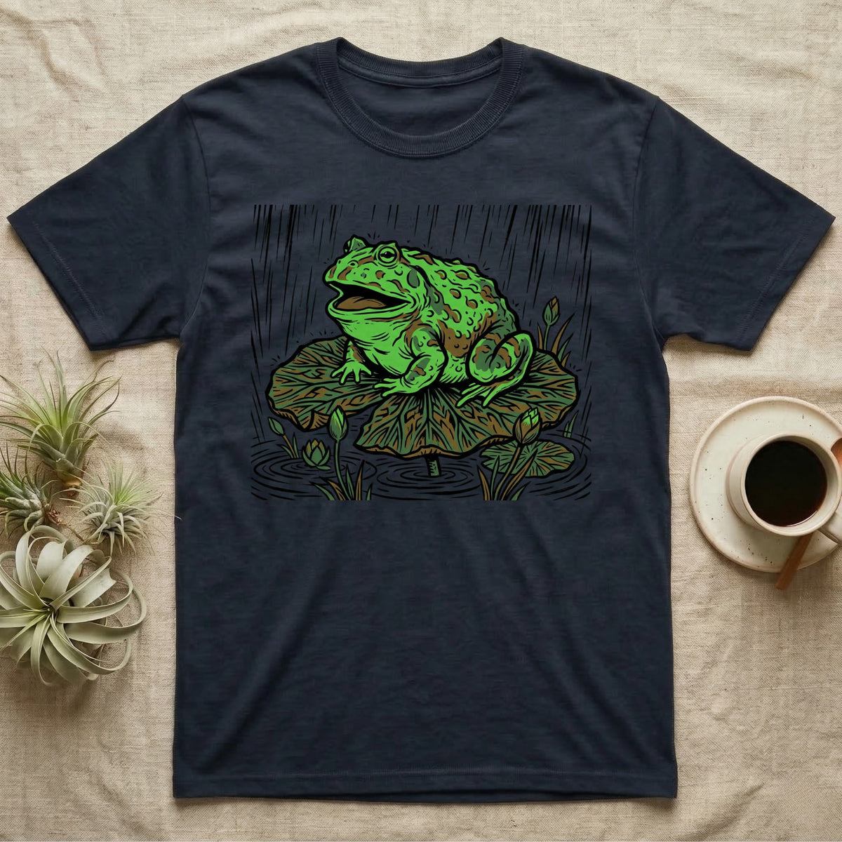 Navy t-shirt featuring a green frog on a lily pad in the rain.