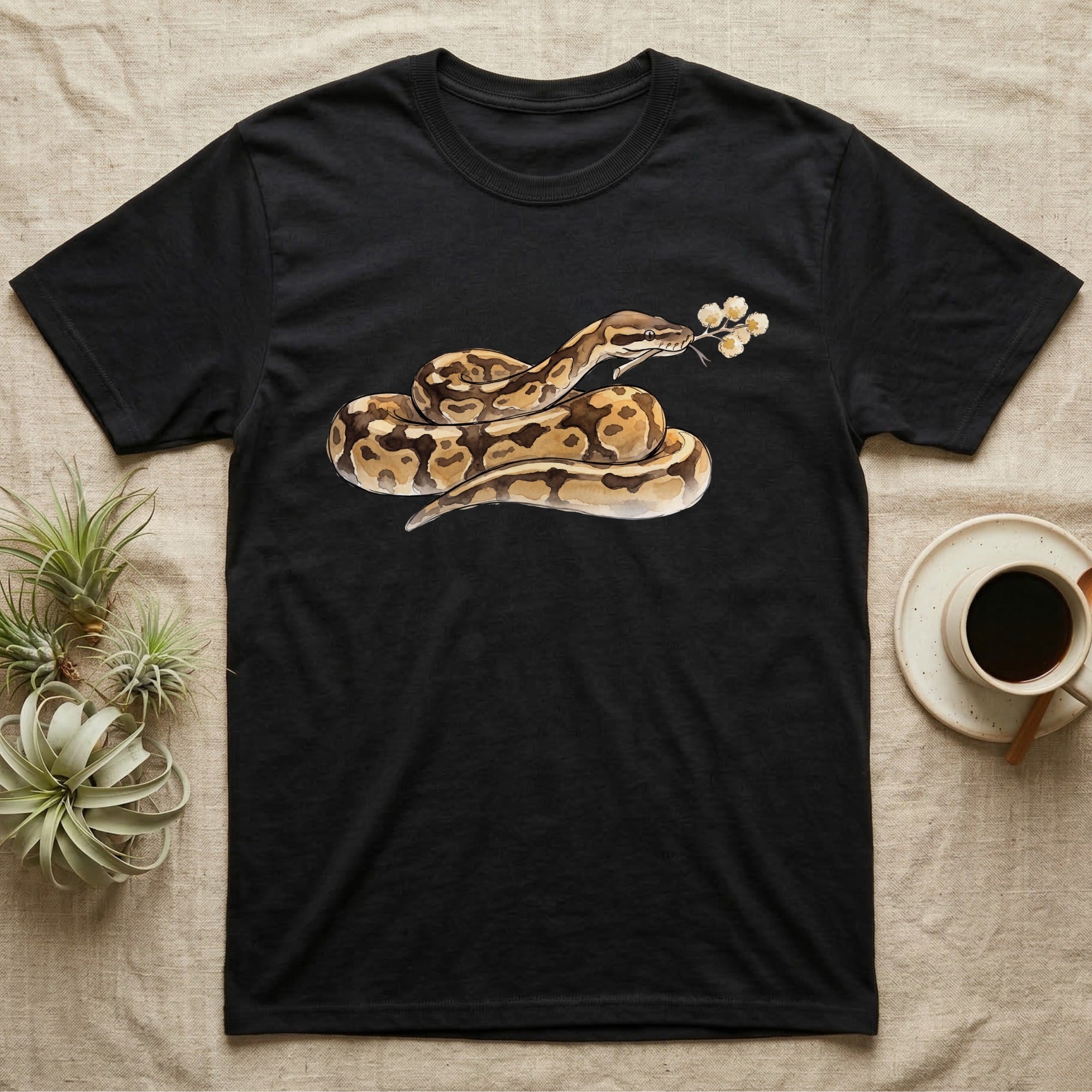 Ball Python Blossom T-Shirt in Black — Watercolor illustration of a tan-and-brown ball python holding an acacia blossom sprig, on a dark grey t-shirt.