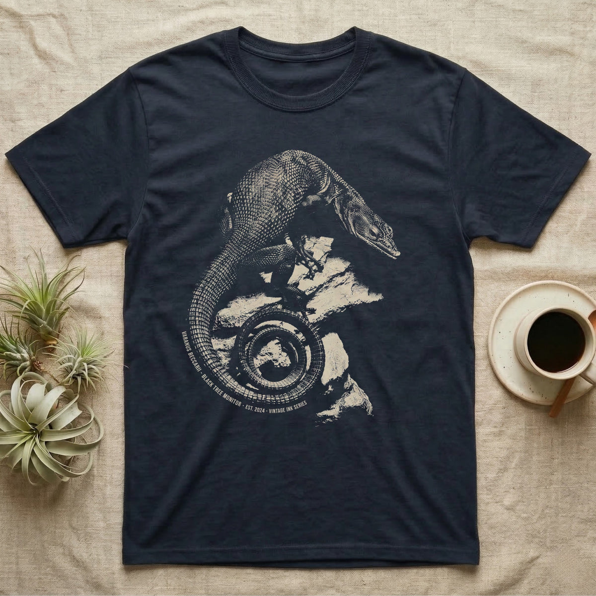 Vintage engraved illustration of a black tree monitor climbing rock with its tail coiled into a badge, arc text reading Varanus Beccarii, Black Tree Monitor, Est. 2024, Vintage Ink Series. — shown on a Navy tee.