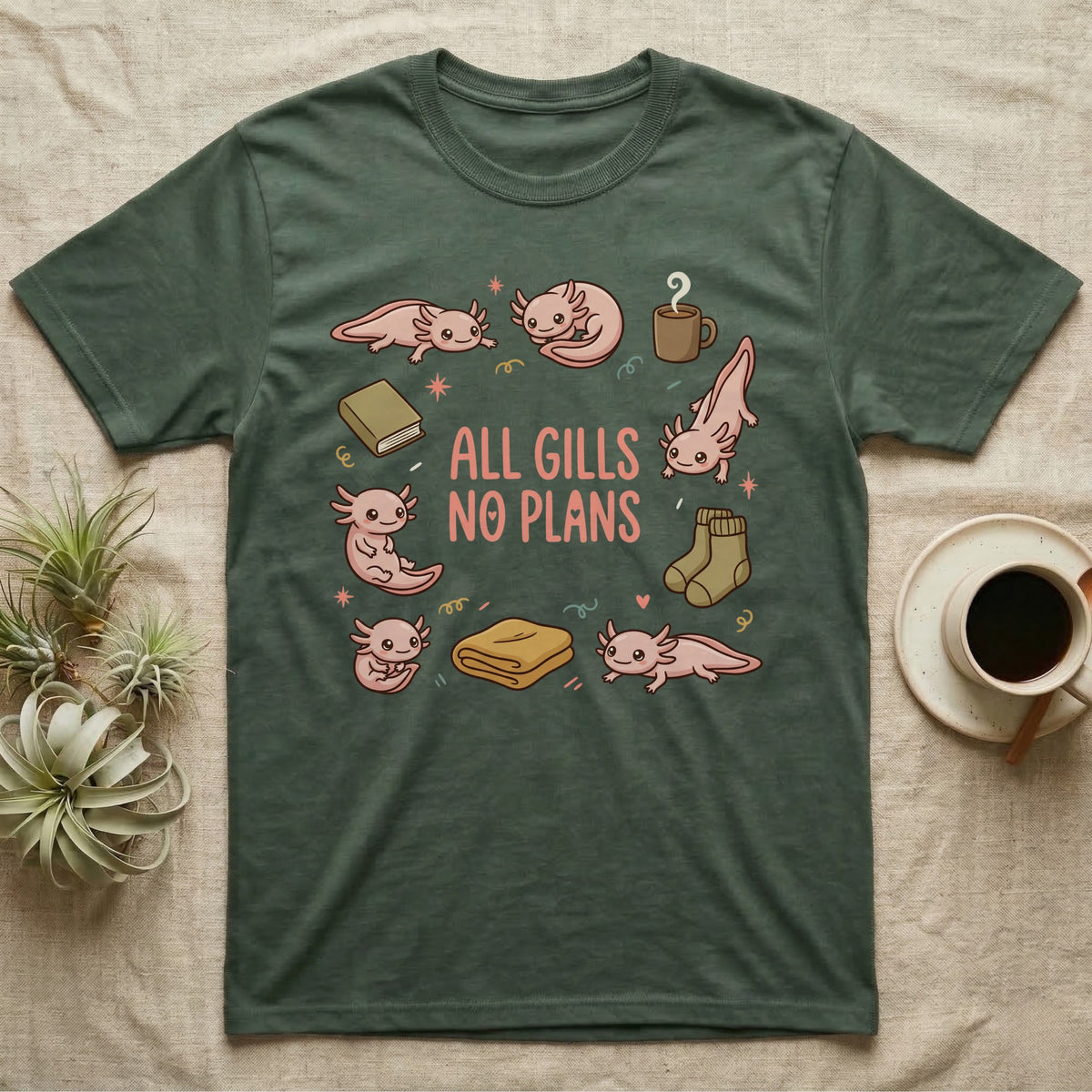 Axolotl All Gills No Plans T-Shirt in Military Green — Cartoon sticker collection of six leucistic axolotls resting among a mug, socks, a blanket and a book, under the words ALL GILLS NO PLANS.