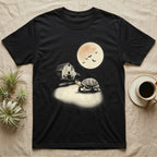 Box Turtle Moonlight T-Shirt in Black — An eastern box turtle mid-step across a moonlit yard, a derelict barn behind it and a large cream moon high right.