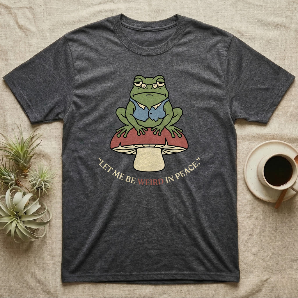 Dark grey t-shirt with a frog on a mushroom and the text "Let me be weird in peace."